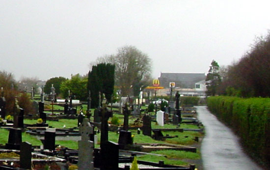Old Graveyard in the foreground with McDonalds, Caseys, Tescos and Church of the Holy Rosary visible in the background