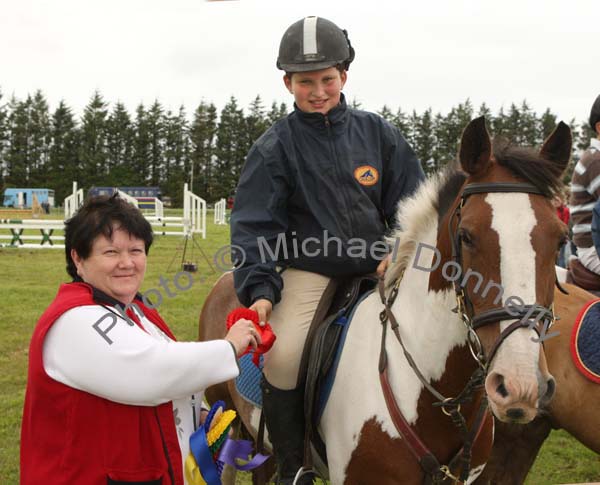 Anne Erdok (Judge) presents 1st prize in the 128 ABC at Claremorris Showjumping section of Claremorris Agricultural Show to Jason Sweeney, Ballina, grandson of Joe Sweeney, Ballina. Photo:  Michael Donnelly