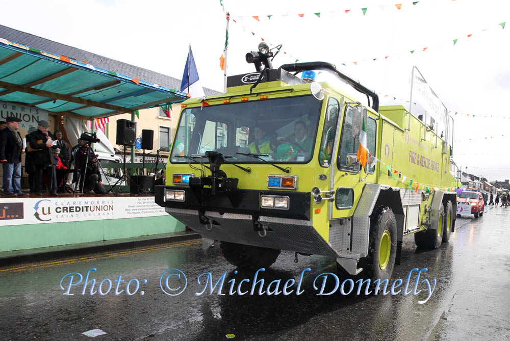 The Knock Airport "Fire and Rescue Service"vehicle dwarfed all of the other "Floats" as it passes the Reviewing stand with Johnny Kirrane on the Microphone at the Claremorris St Patricks Day Parade. Photo: © Michael Donnelly